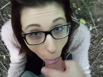 Geeky brunette is on her knees swallowing a dick in the forest